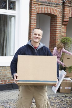 Professional piano movers handling an upright piano in a Canary Wharf apartment building